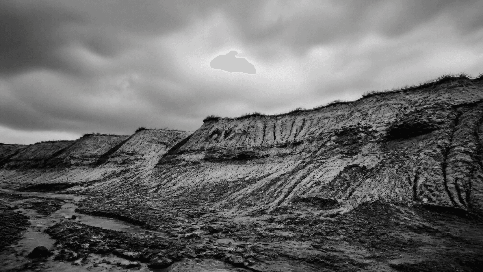 A raw clay quarry under a heavy sky