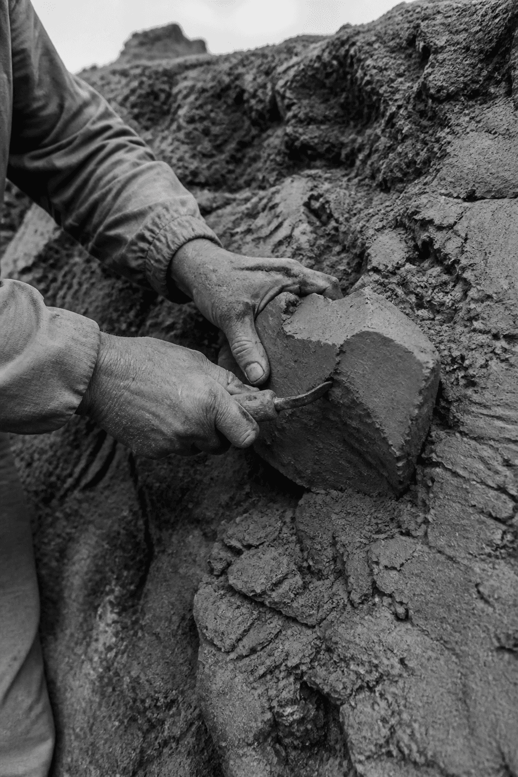 Hands gathering clay from the quarry wall